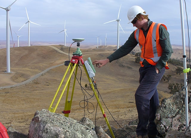 Engineering surveyor on-site a wind farm project using surveying equipment 